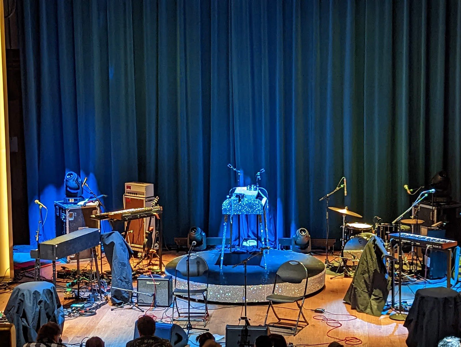 View from above of the Echo Lounge music hall stage before a show, gear and amps set up on a wood floor in front of a blue velvet curtain
