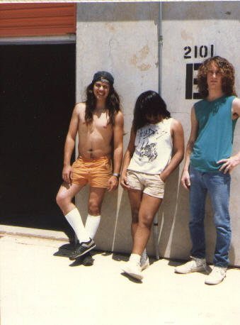 Long-haired young men standing against the concrete wall of a storage unit numbered 2101, the Rotting Corpse practice space in Arlington