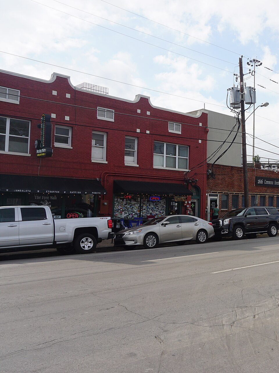 Red brick two-story storefronts on Commerce Street in Deep Ellum in 2017, with parked cars along the curb