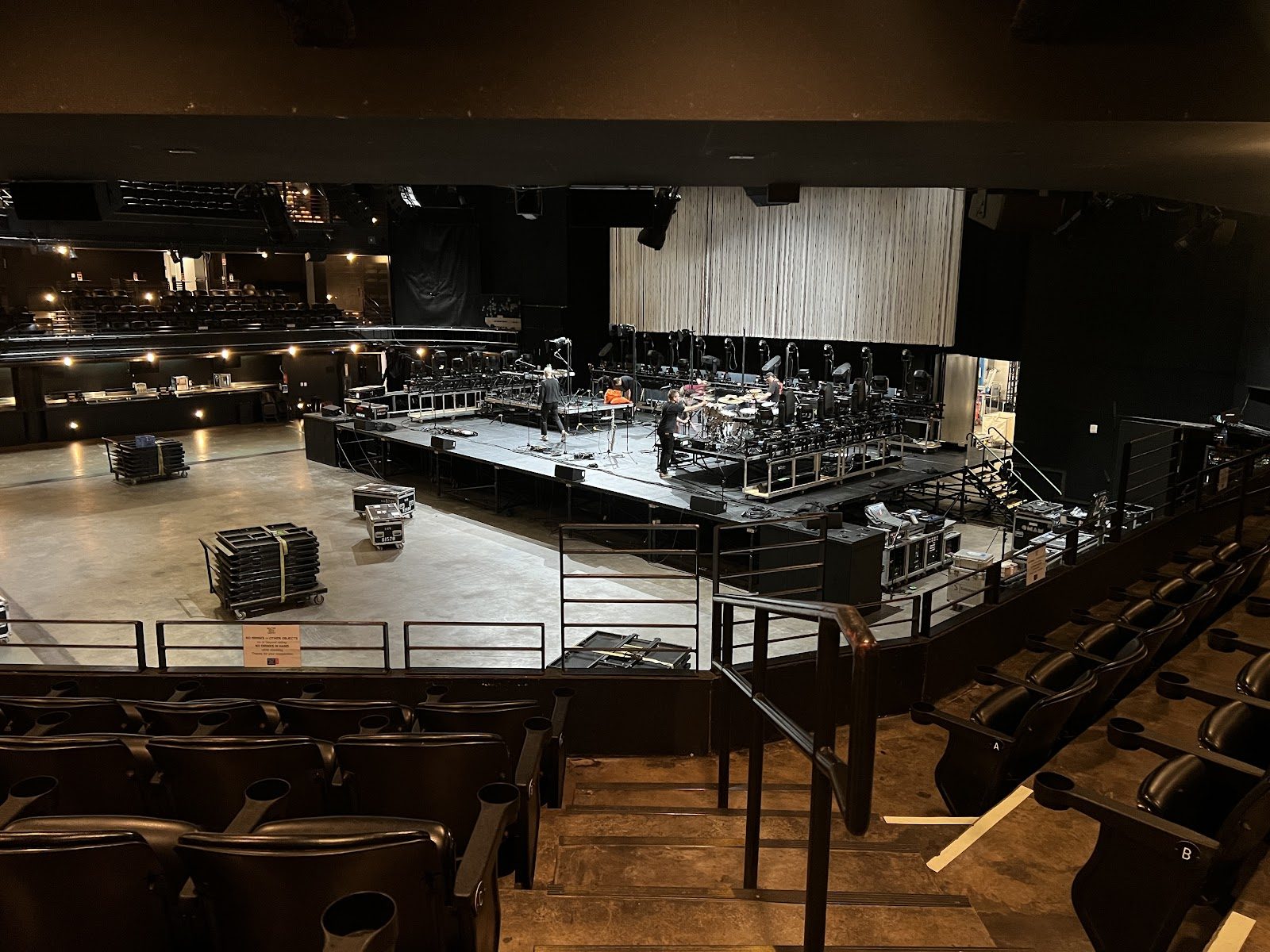 The empty main floor and tiered black seats of ACL Live at the Moody Theater, with a crew setting up drums and lights on the stage