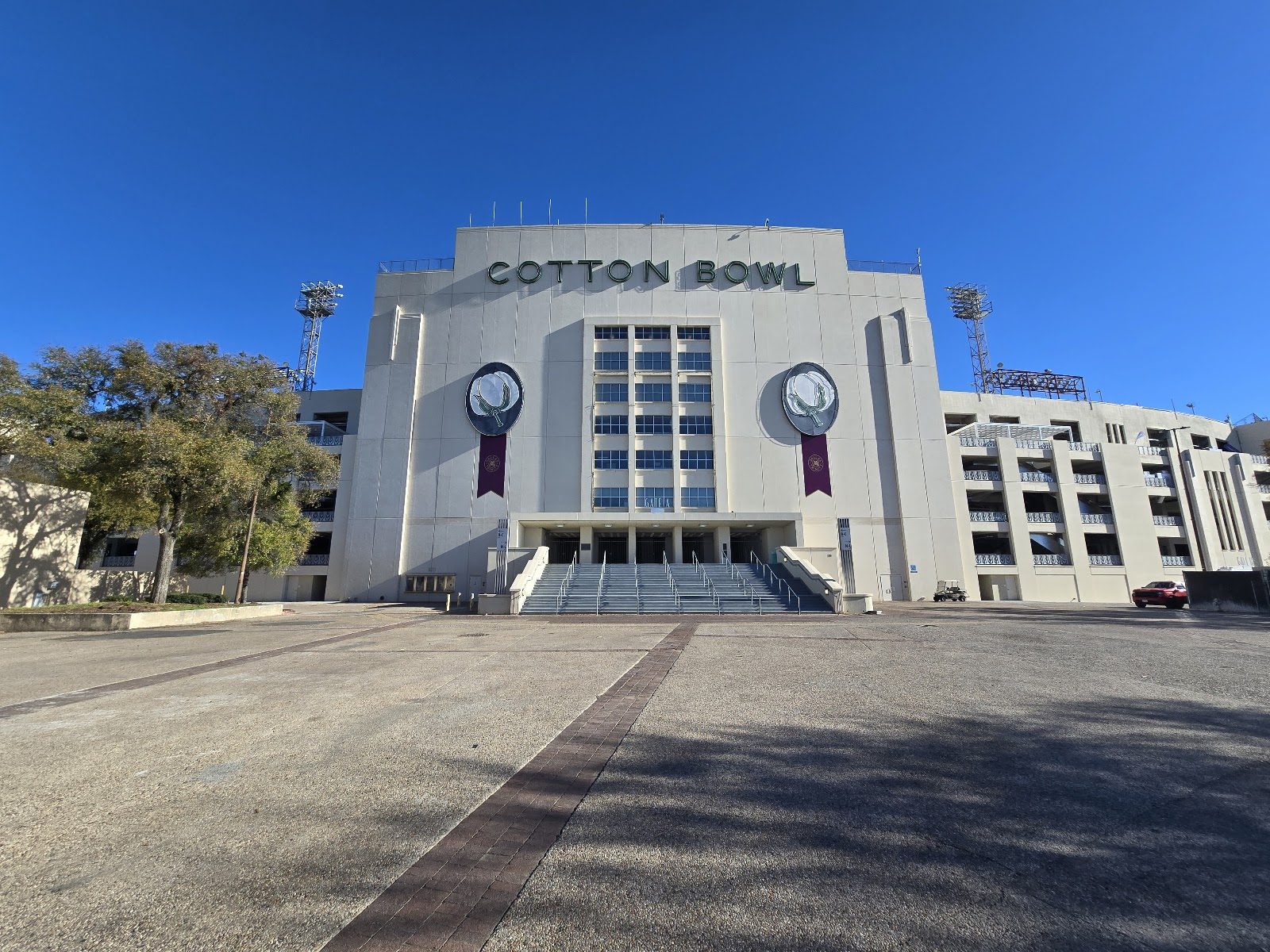 The pale Art Deco entrance of the Cotton Bowl stadium in Fair Park, its name in green letters above a central staircase, under a clear blue sky