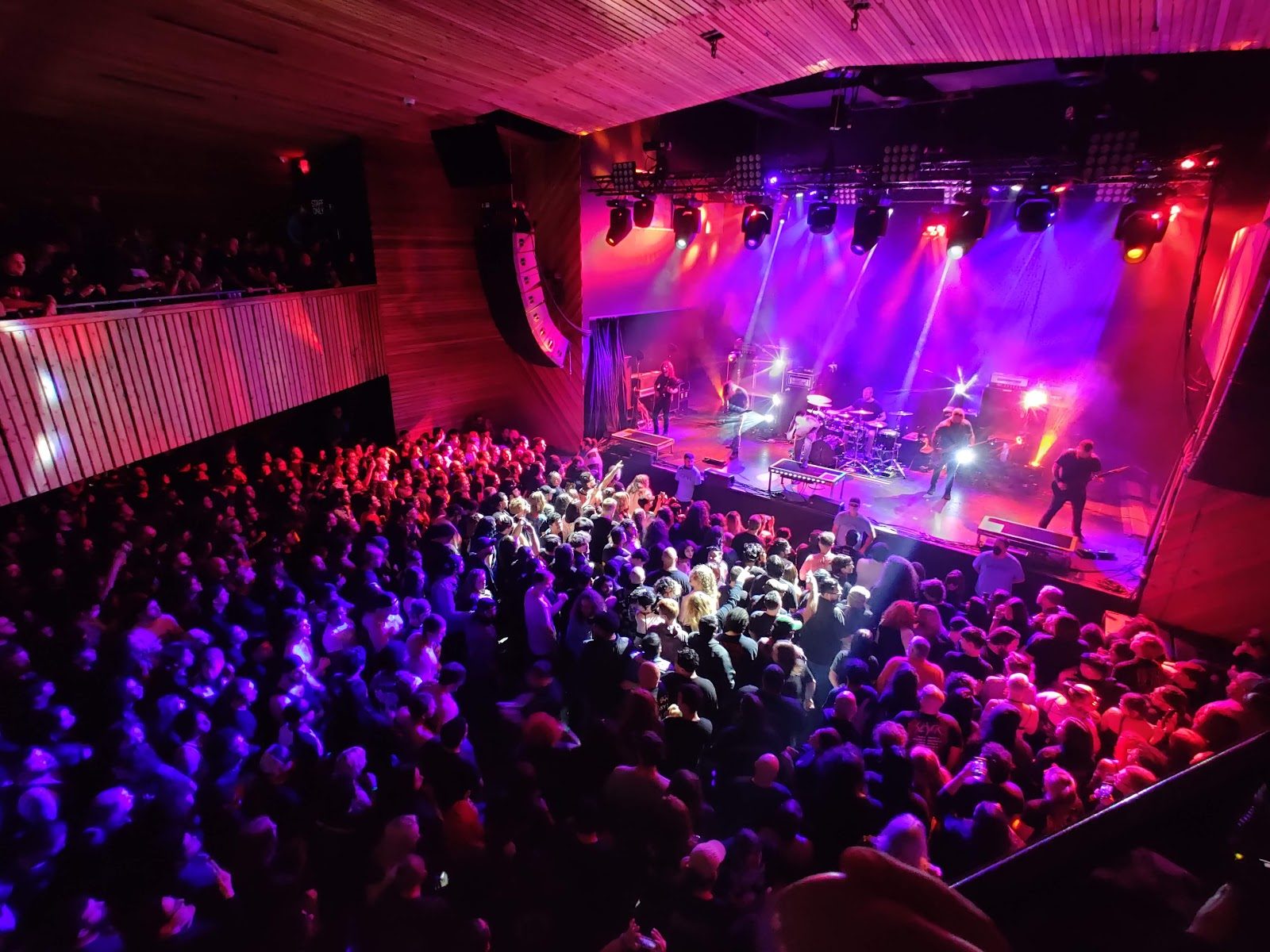 A packed indoor room at White Oak Music Hall seen from the balcony, with a band on a stage lit purple and red